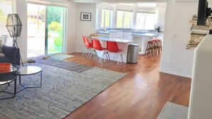 Un vaste espace de vie comprenant une cuisine et un coin repas, avec un grand îlot central, des chaises rouges et un design moderne.