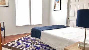 A bedroom with a bed, a window, a door, and a rug.