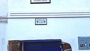 A hotel entrance with a blue door, a sign reading "El Ave Azul", and two wall-mounted lanterns. - El Ave Azul Boutique Hotel Cusco (Cusco)