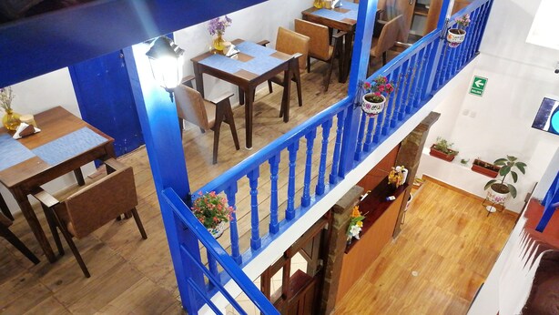 A multi-level restaurant with wooden flooring, blue railings, and potted plants. - El Ave Azul Boutique Hotel Cusco (Cusco)