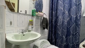 Une salle de bain avec un lavabo blanc, des toilettes et un rideau de douche.