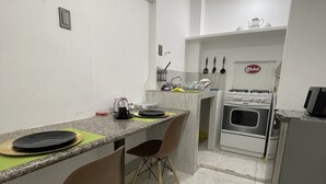 Une cuisine compacte comprenant un coin repas, une cuisinière et un réfrigérateur.