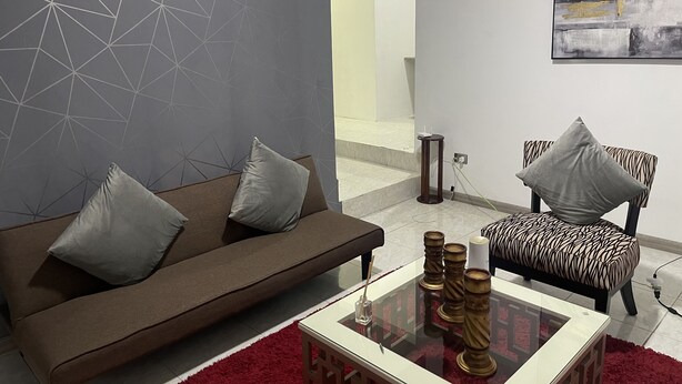 Un salon moderne avec un canapé marron, un fauteuil à motifs et une table basse en verre.