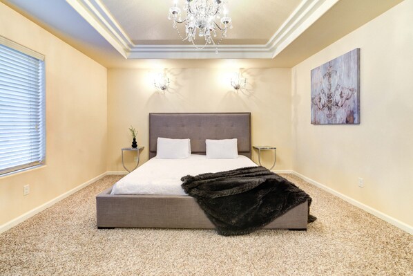 Quarto com uma cama grande, duas mesas de cabeceira, um candelabro e um quadro na parede.