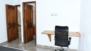 Um quarto com uma escrivaninha de madeira, uma cadeira de escritório preta e duas portas de madeira.
