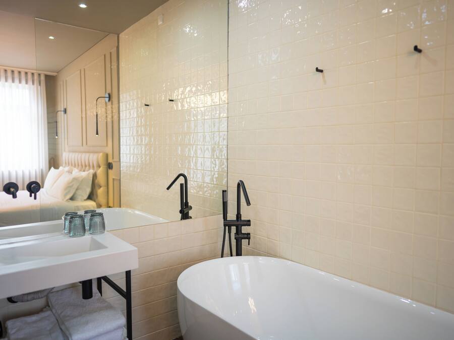A bathroom with a white bathtub, a sink, and a mirror.