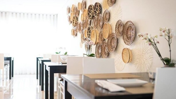 A hotel reception area with a modern design, featuring a wall adorned with woven baskets and a white fluffy decorative element. - Santo Thyrso Hotel (Santo Tirso)