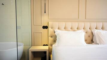 A hotel room with a large bathtub, a tufted headboard, and a bedside table with a lamp.