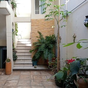 A narrow outdoor staircase leading to a second floor, surrounded by potted plants and a stone wall. - Bokatrip Jalatlaco (Oaxaca)