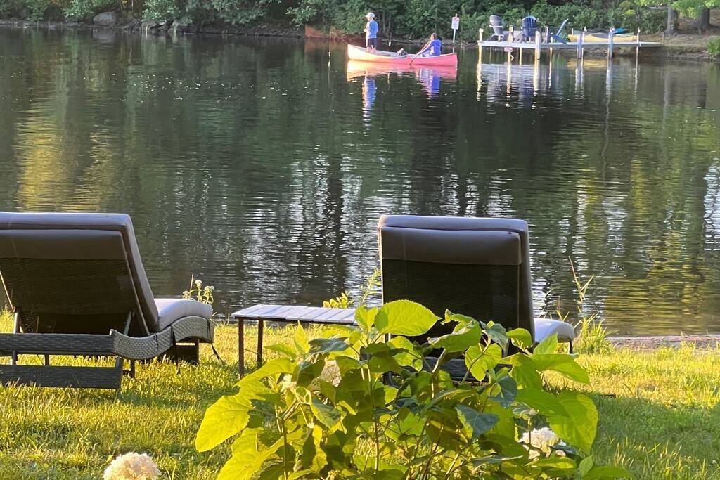En lugn och vacker plats vid sjön, med solstolar och en brygga där det finns kanoter.