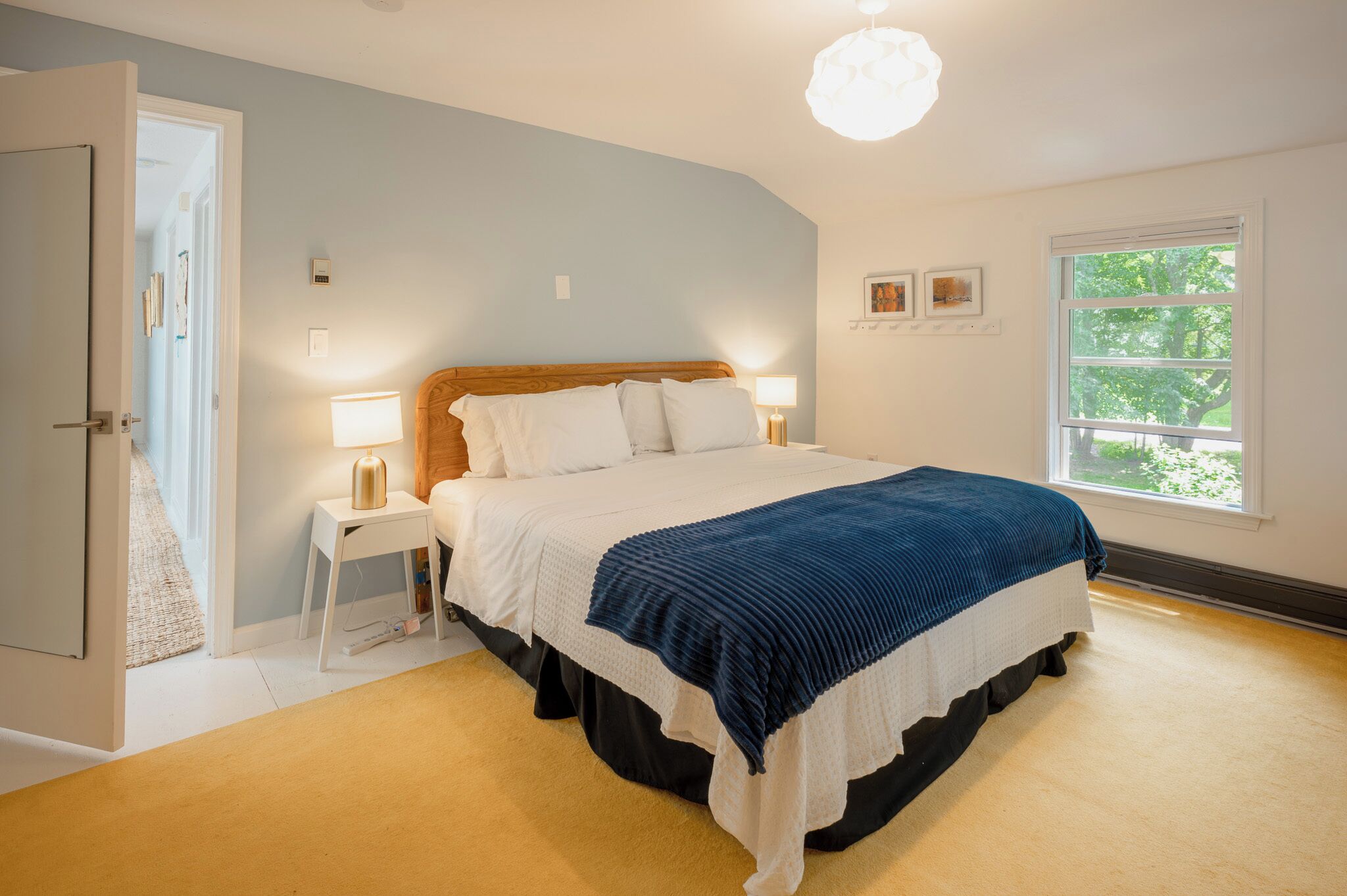 Une chambre à coucher avec un lit, des tables de chevet, une fenêtre et une porte.