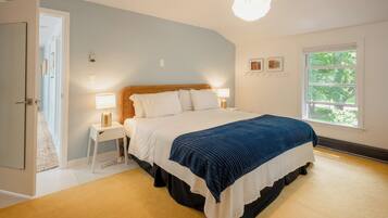 Une chambre à coucher avec un lit, des tables de chevet, une fenêtre et une porte.