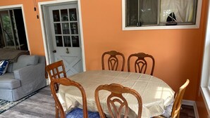 Ein Essbereich mit Tisch und vier Stühlen, einer Couch und einer Tür.