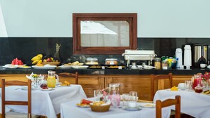 A breakfast buffet with various food items and beverages, a coffee station, and a framed picture on the wall. - AIOLOS HOTEL & DISCOVERIES (Cruz)