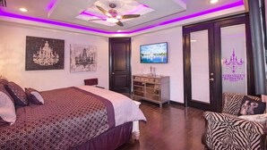 A modern bedroom with a bed, a TV, a chandelier, and a ceiling fan. - 🕯Versaille’s Residence ™ (McAllen)