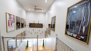 Un pasillo de hotel con carteles de películas enmarcados, una escalera y un ventilador de techo.