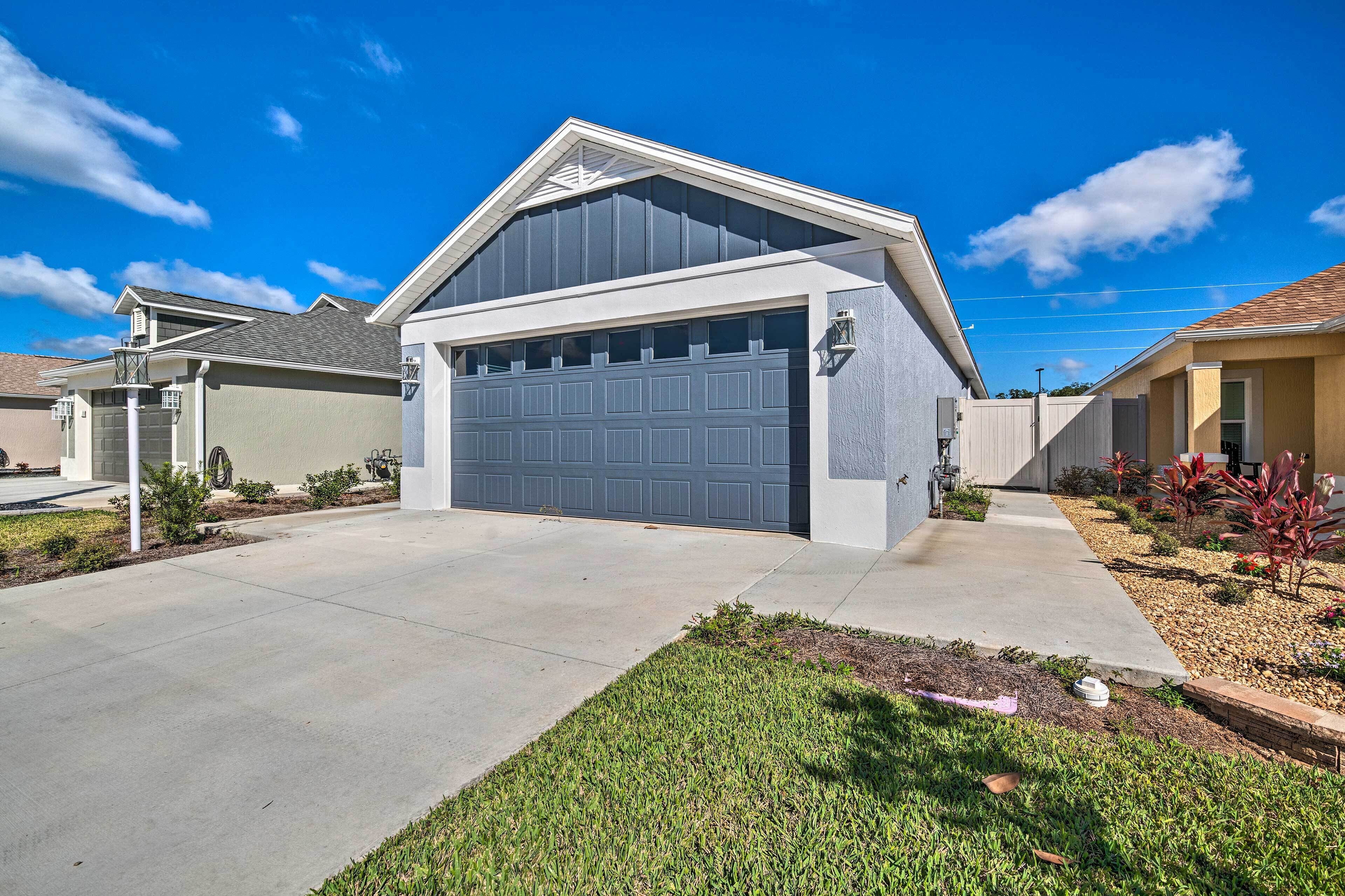 A residential garage with a large door, a driveway, and a well-maintained lawn.