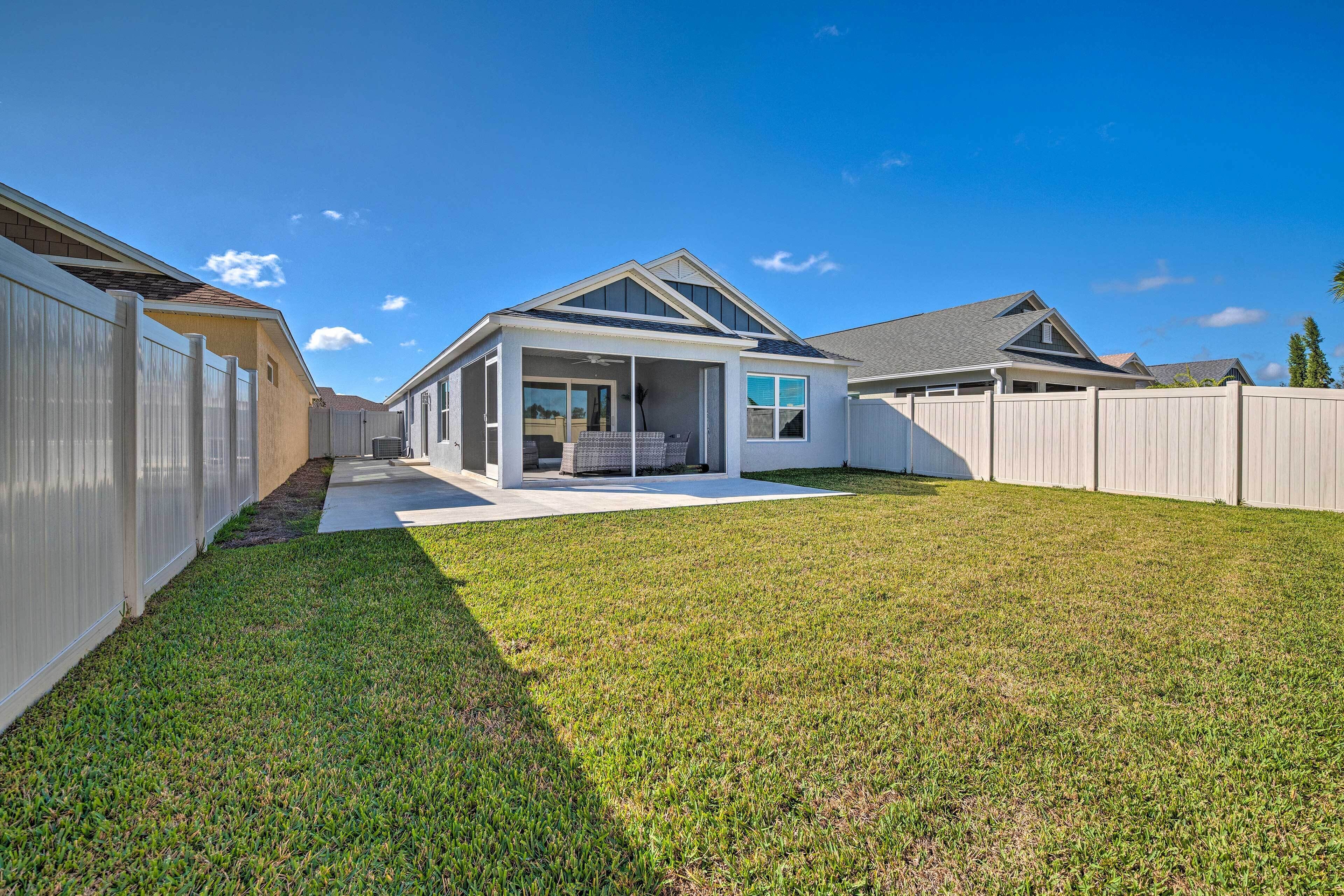 A residential property with a covered patio, a fenced backyard, and a clear blue sky.