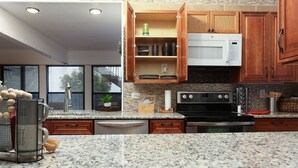 Eine moderne Küche mit Granit Arbeitsplatten, Holzschränken, einer Mikrowelle und einem Backofen.
