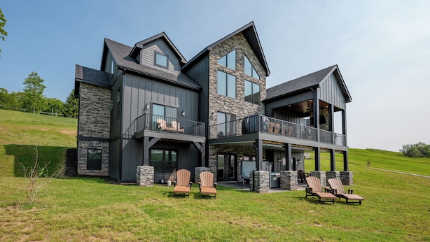 A modern multi-story house with a large balcony and outdoor seating area.