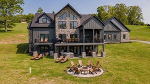 A two-story house with a stone facade, large windows, and a patio with outdoor seating.