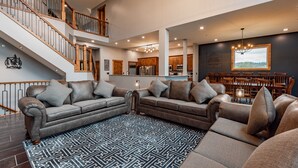 A spacious living area with a large sectional sofa, a patterned rug, and a staircase leading to an upper level.