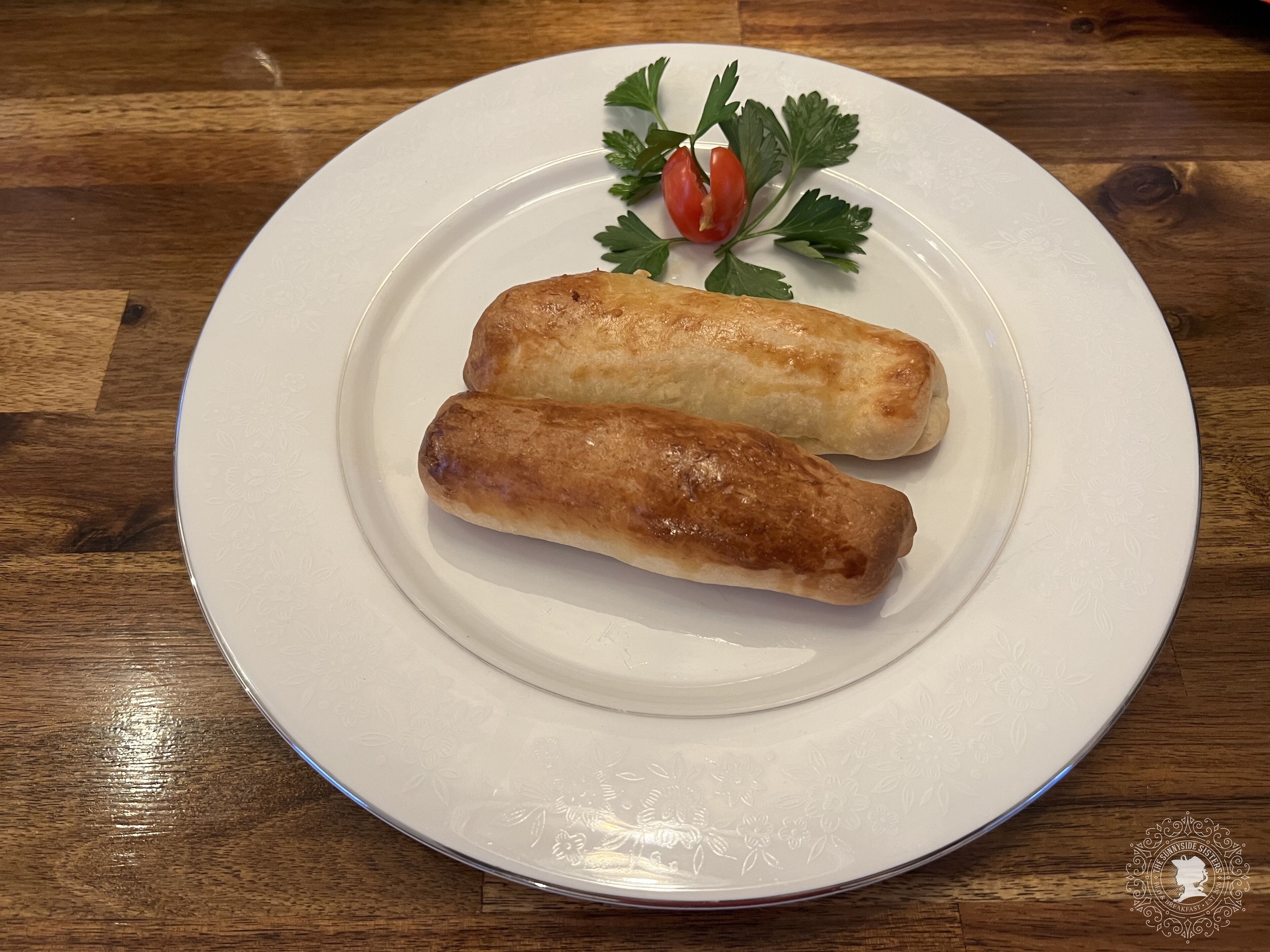 A white plate with two golden-brown pastries on a wooden table.