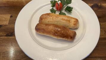 A white plate with two golden-brown pastries on a wooden table.