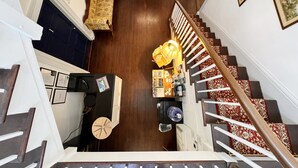 A spacious living area with a wooden staircase, a sofa, a coffee table, and a bookshelf. - The Sunnyside Sisters Bed and Breakfast (Clarksville)