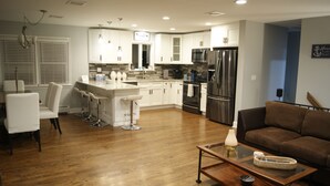 A modern kitchen with white cabinets, stainless steel appliances, and a bar area. - BestOBothWorlds*2GWifi@HandcraftedWoodTerrace~Firepit#GameRoom (Jefferson)
