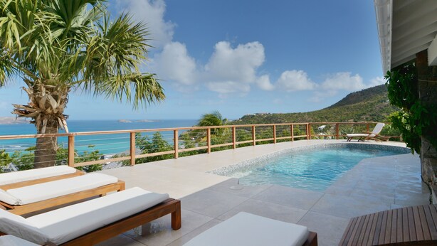A poolside area with lounge chairs and a view of the sea.