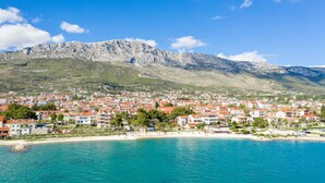 A coastal town with buildings along the beach, a mountain in the background, and clear blue waters. - Luxury Villa Imperio with Pool (Kaštel Gomilica)