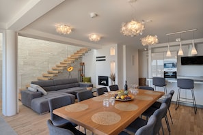 Un espace de vie moderne avec une table à manger en bois, des canapés gris et un escalier avec des marches en bois.