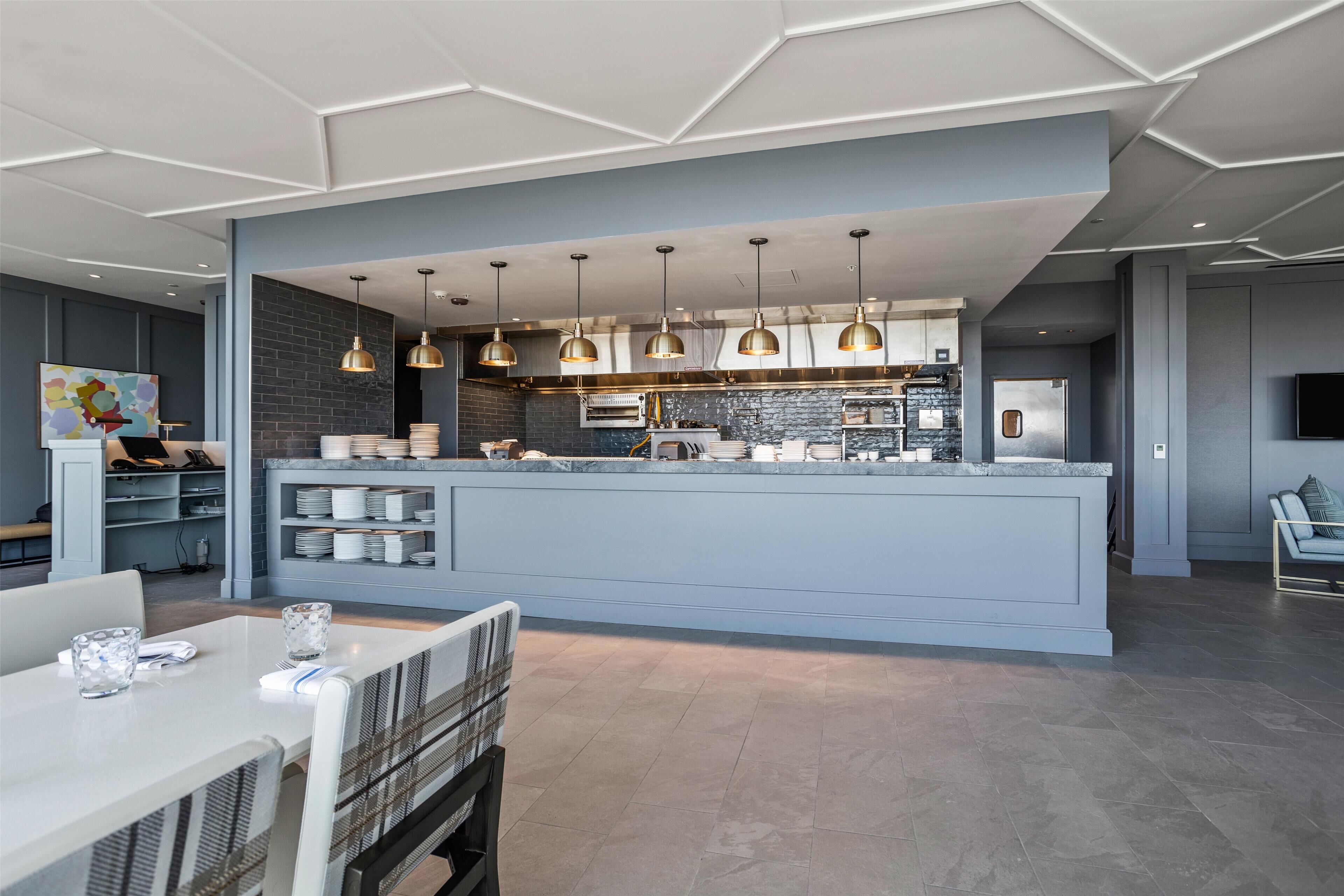 A modern kitchen with a central island, pendant lighting, and a dining area with a table and chairs.