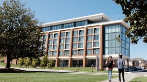 A modern building with a glass facade, a flat roof, and a central entrance.