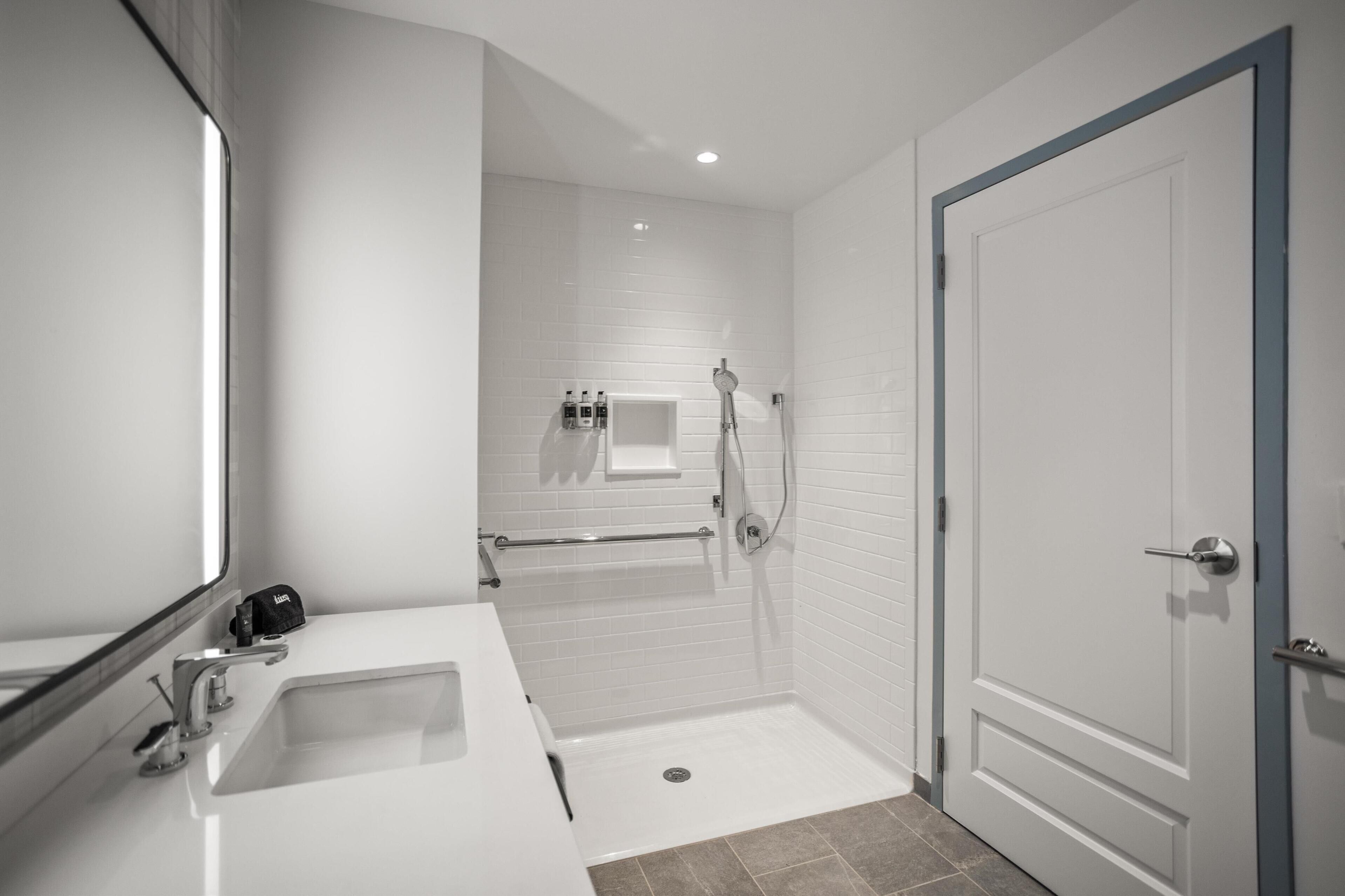 Un bagno moderno con lavandino, specchio e doccia bianchi.