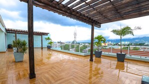 A spacious rooftop terrace with wooden flooring, potted plants, and a view of the cityscape. - luxury Condo at Kensington Gates (Kingston)