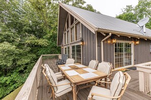 Eine Holzterrasse mit Tisch und Stühlen, umgeben von üppiger Vegetation.