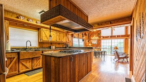 Une cuisine spacieuse dotée de meubles en bois, d’un îlot central et d’une grande fenêtre qui laisse entrer la lumière naturelle.
