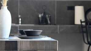A modern kitchen with a minimalist design, featuring a dark countertop, a white vase with dried pampas grass, and a black bowl on a plate. - Pulso Valle de Guadalupe (Valle de Guadalupe)