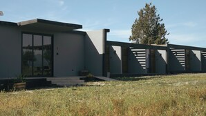 A modern building with a large glass door, a concrete facade, and a wooden deck. - Pulso Valle de Guadalupe (Valle de Guadalupe)