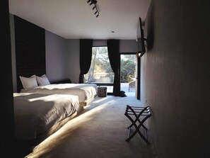 Une chambre avec un grand lit, une petite table et une vue sur l’extérieur.