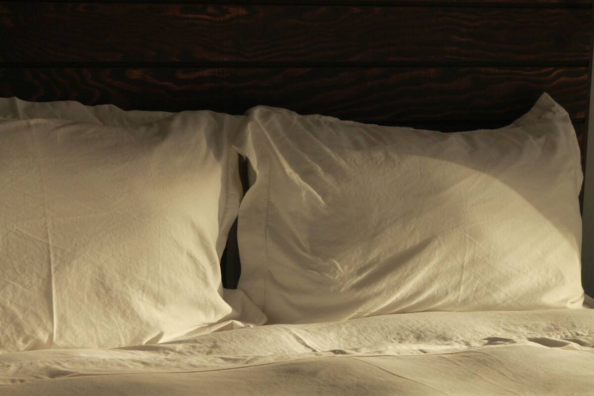 Ein Bett mit weißer Bettwäsche und einem Holzkopfteil.