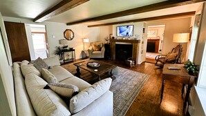 Un salon chaleureux avec une cheminée, un téléviseur et un canapé confortable.