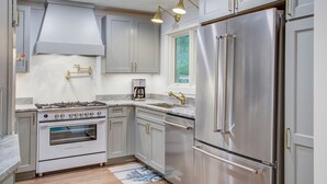 Una cocina moderna con electrodomésticos de acero inoxidable, armarios blancos y un ventanal que proporciona luz natural.