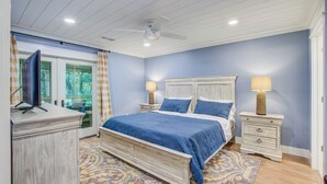 Un dormitorio con cama, mesitas de noche, escritorio y ventilador de techo.