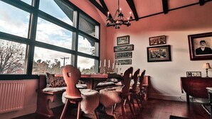 Un comedor con un ventanal grande, muebles de madera y cuadros en la pared.