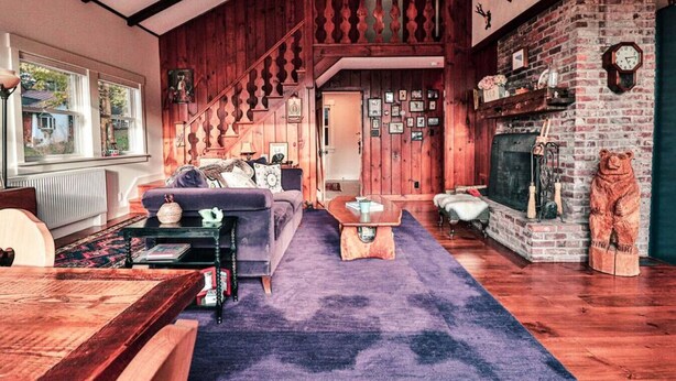 Una sala de estar acogedora con una escalera de madera, una chimenea y una escultura de un oso.