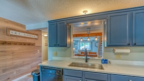 A kitchen with blue cabinets, a dishwasher, and a wooden wall with a sign reading "SKI LODGE". - Loon Mountain Condo- Walk to Main Street! (Lincoln)
