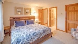 A bedroom with a bed, bedside tables, a lamp, and a chair. There are two doors and a closet. - Loon Mountain Condo- Walk to Main Street! (Lincoln)
